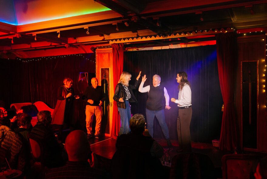 A small group of people on stage, standing around casually. 
