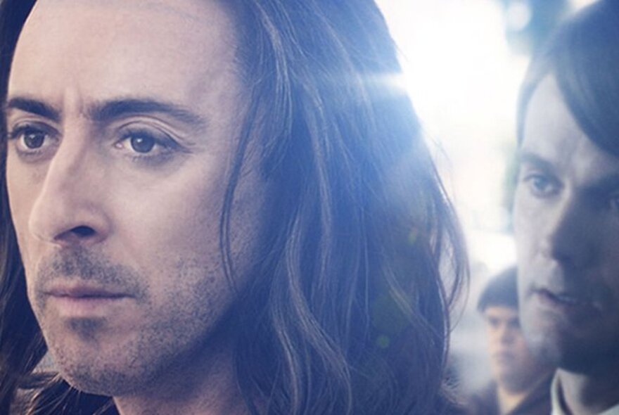 Actor Alan Cumming in a movie still, with long hair and eye makeup.