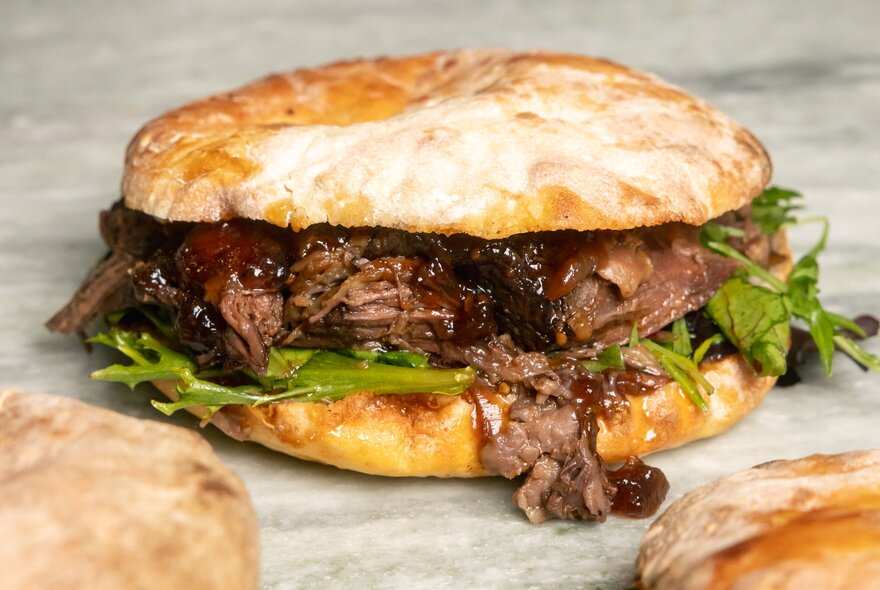 Bread bun with steak filling on a bench.