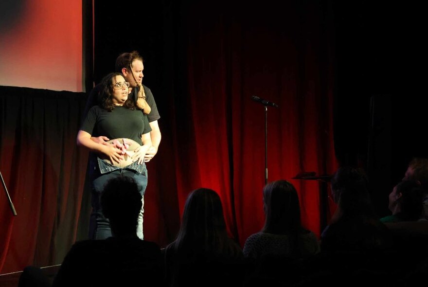 Two performers on a small theatre stage improvising a show in front of an audience.