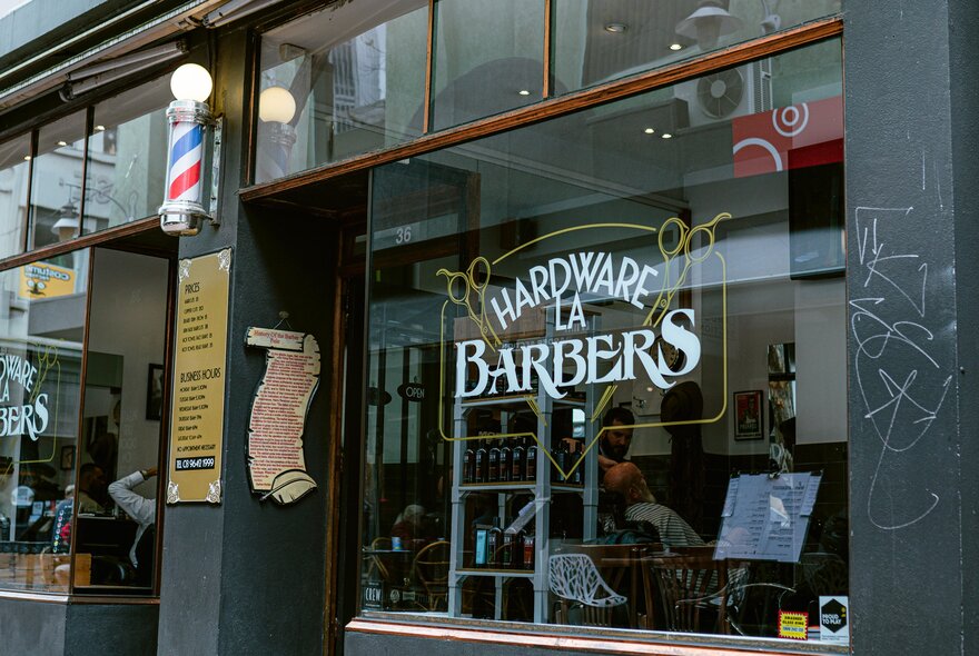 Exterior of Hardware La Barbers with a traditional revolving pole out the front. 