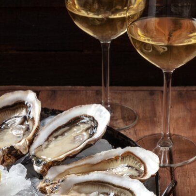 A plate of oysters and two glasses of white wine. 