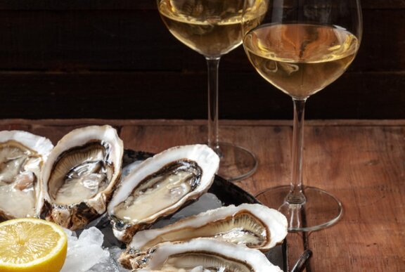 A plate of oysters and two glasses of white wine. 