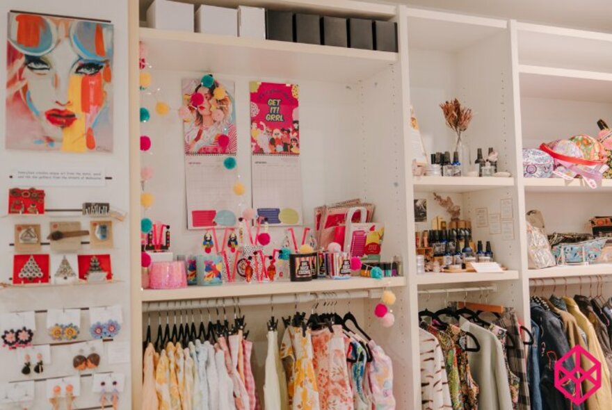 Retail space showing white shelves of items including clothing, stationary, jewellery and other crafts.