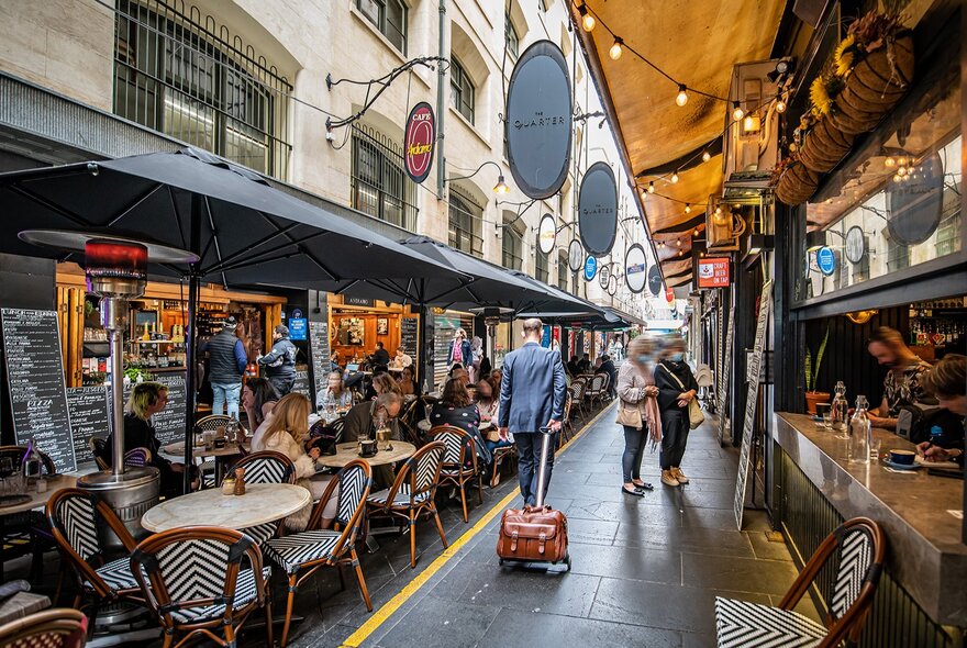 A busy laneway with cafe seating down the middle.