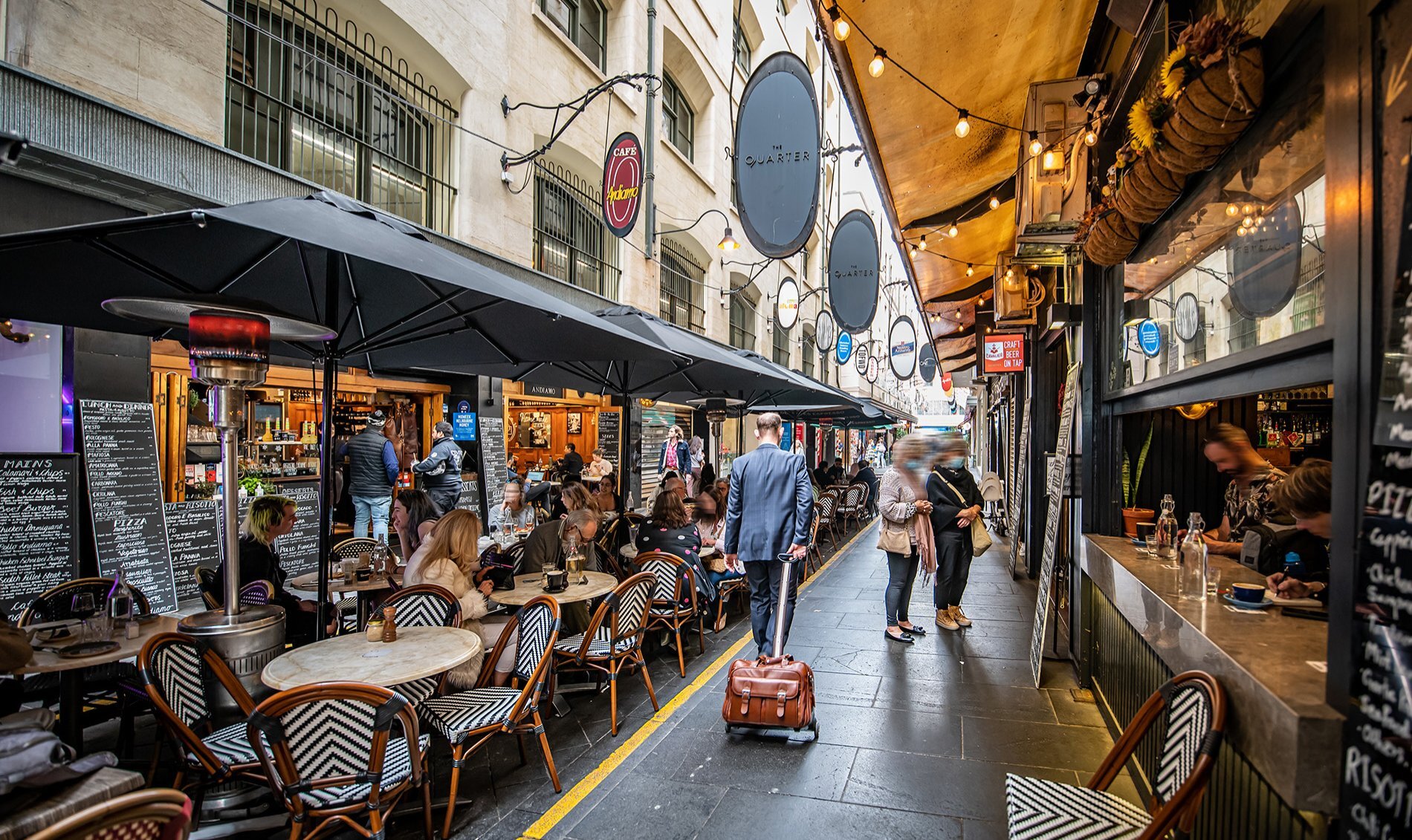 A busy laneway with cafe seating down the middle.