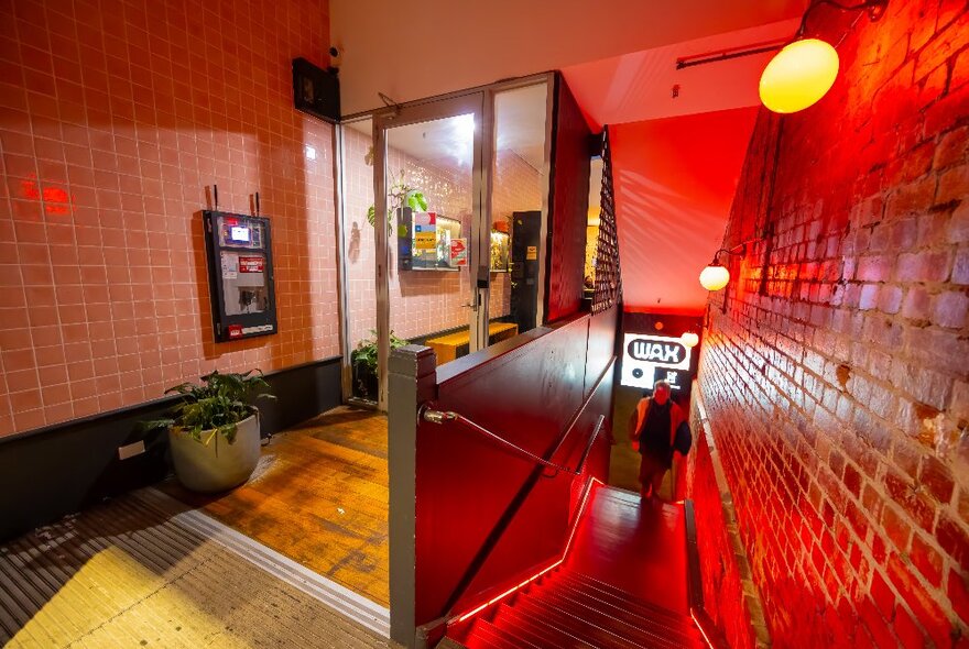 A man is walking up the stairs from a basement bar.