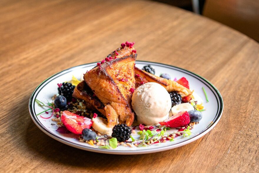 Plate of toasted waffles with fresh fruit and a scoop of ice-cream.