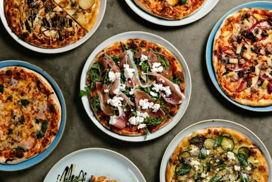 Seven different types of pizzas on display.