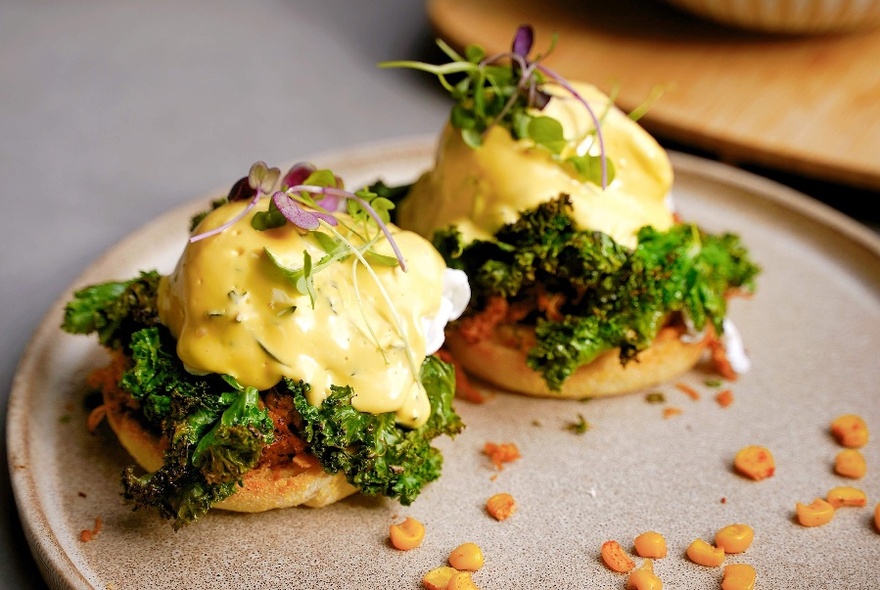 Two poached eggs on small muffins on light brown ceramic plate.