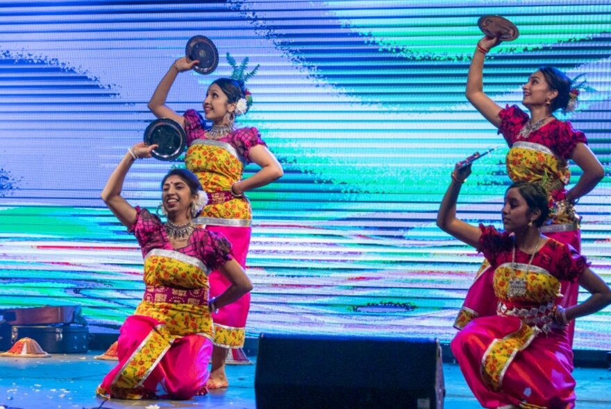 Dancers in traditional dress performing on a brightly decorated stage.