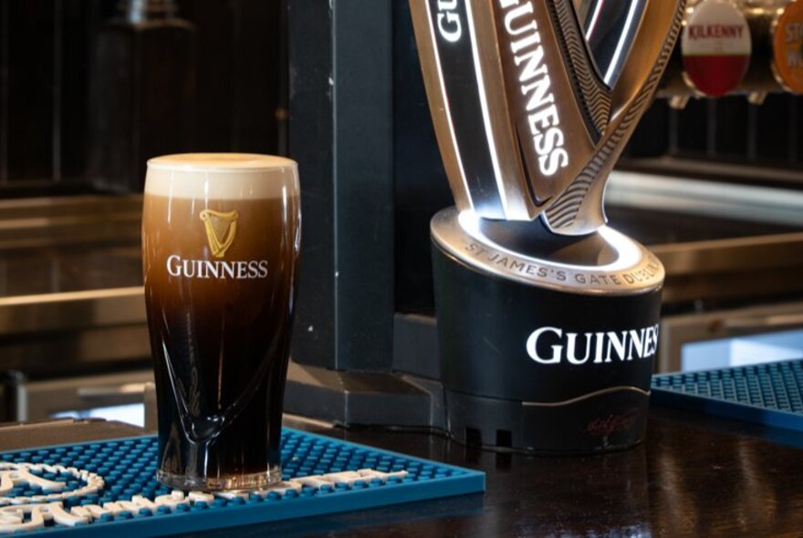 A pint of Guinness next to a GUinness pub counter-top display.