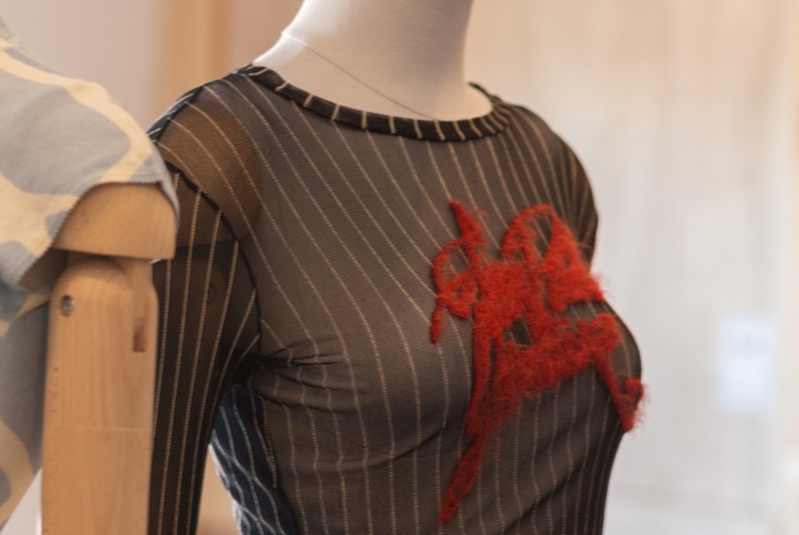 Mannequin wearing a striped black gown with red detail.
