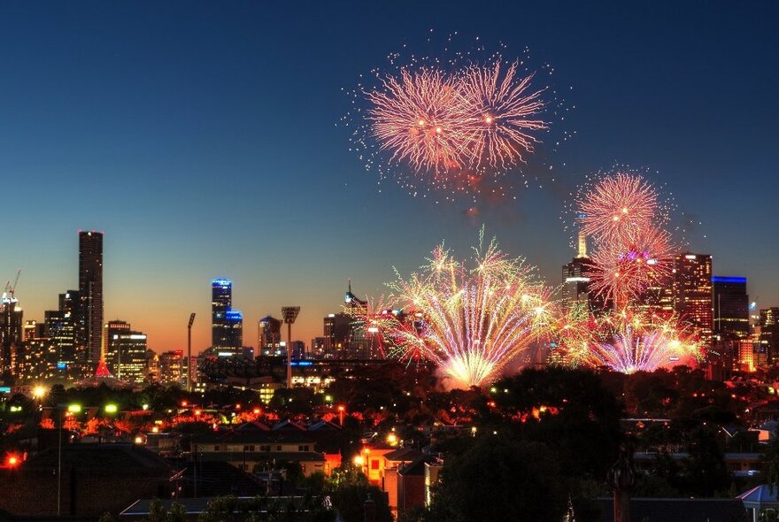 Fireworks exploding at night over the Melbourne city skyline.