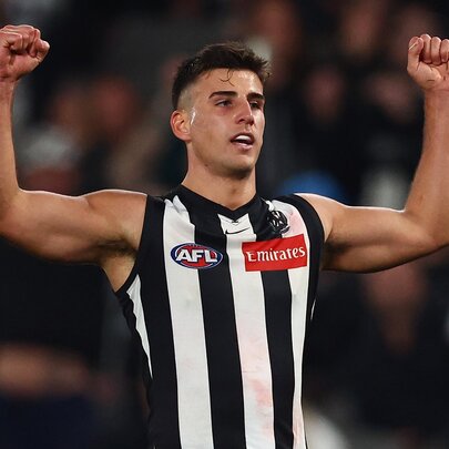 Collingwood AFL football player punching both arms in the air during a match.