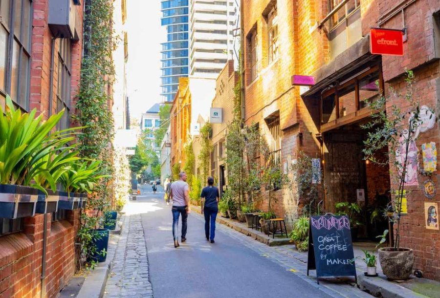 A couple walking down a laneway past brick buildings
