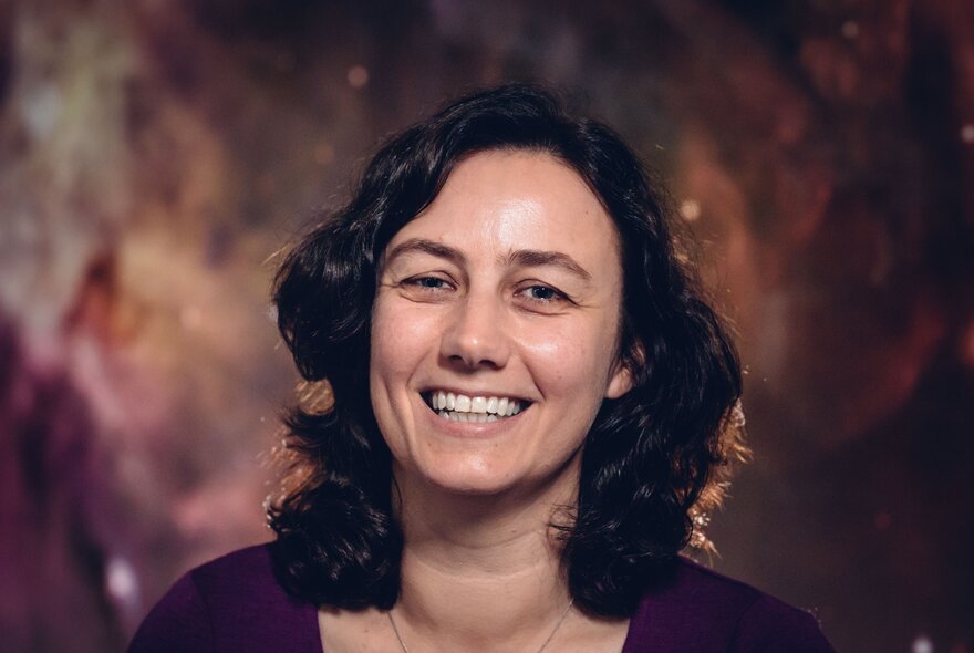 Head and shoulders of astronomer Dr Tanya Hill; she is smiling and has curly dark hair framing her face. 