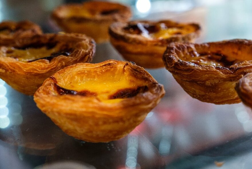 Small flaky sweet pastry tarts on a glass display counter.