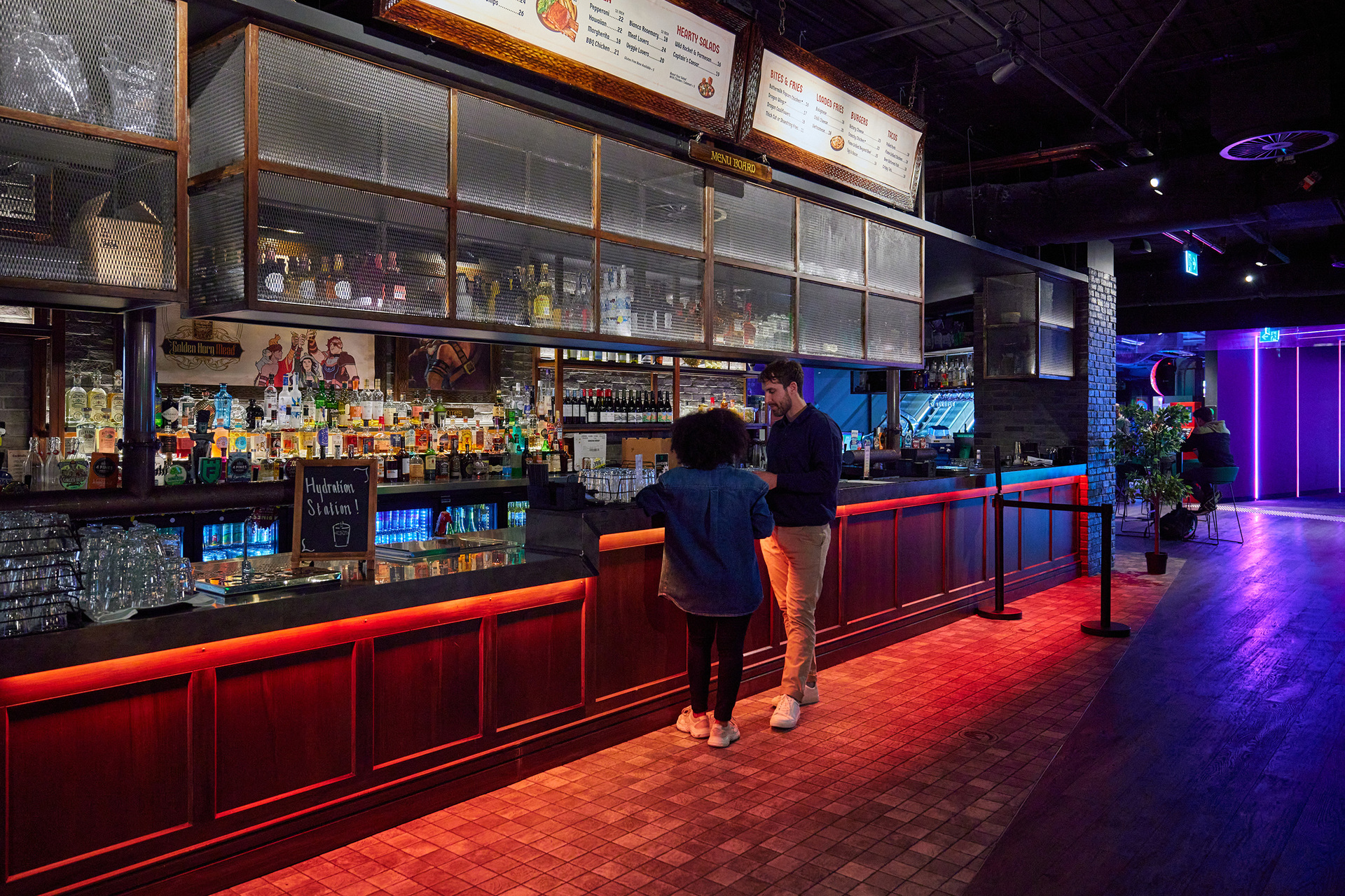 Two friends are ordering a drink at a bar