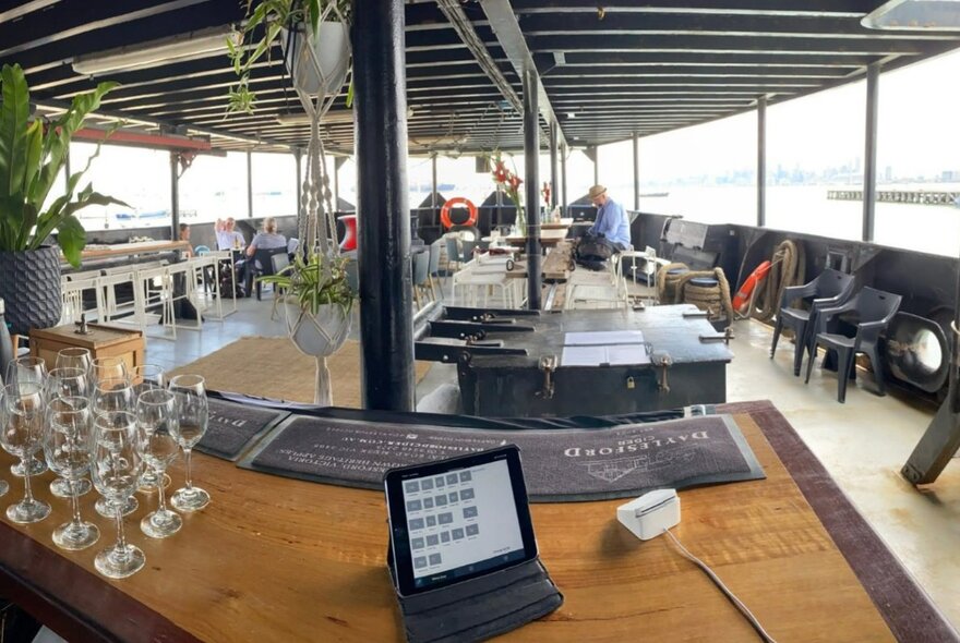 Inside the open stern of a boat with glasses lined up on a bar.