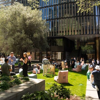 An outdoor gathering of people in a small park the sun with several lounge chairs