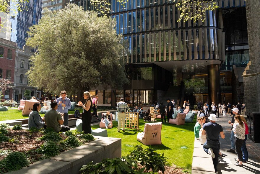 An outdoor gathering of people in a small park the sun with several lounge chairs