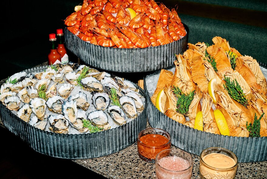 Heaped displays of oysters and seafood with bowls of sauces.