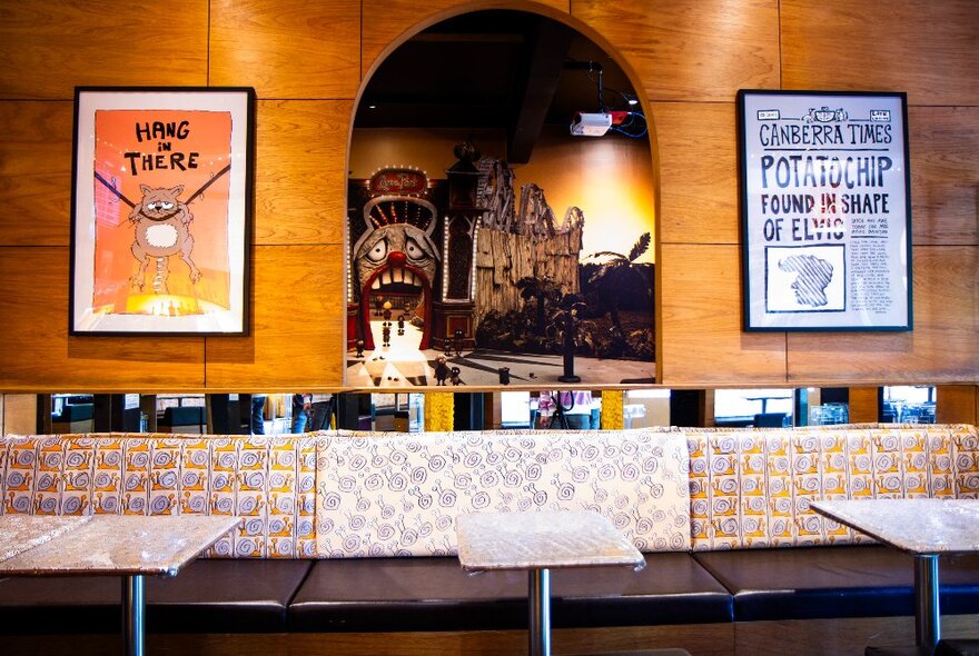 Bar with metallic counter and tables, wooden bar area with Luna Park illustration in cut-out archway.