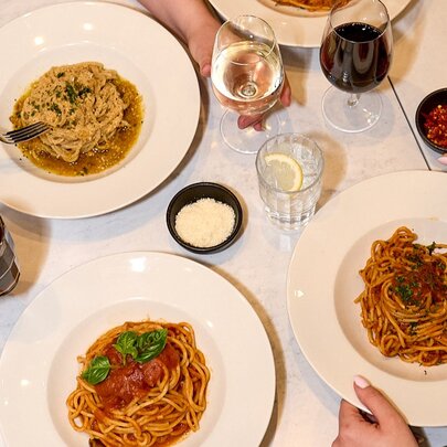 A dinner table with pasta and wine.