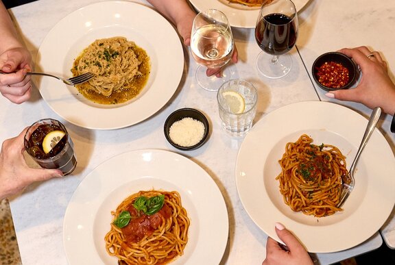 A dinner table with pasta and wine.