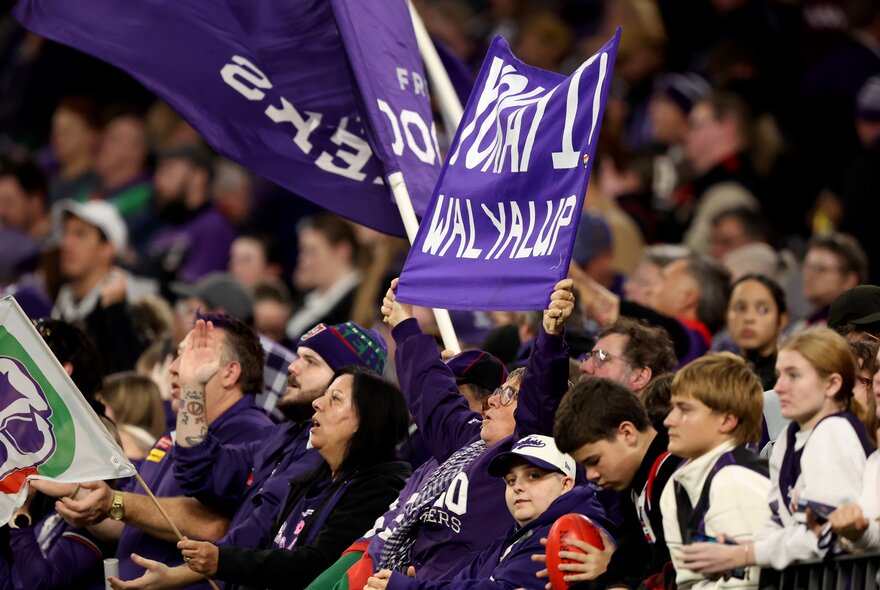 Fremantle AFL fans in the stands with banners and flags.