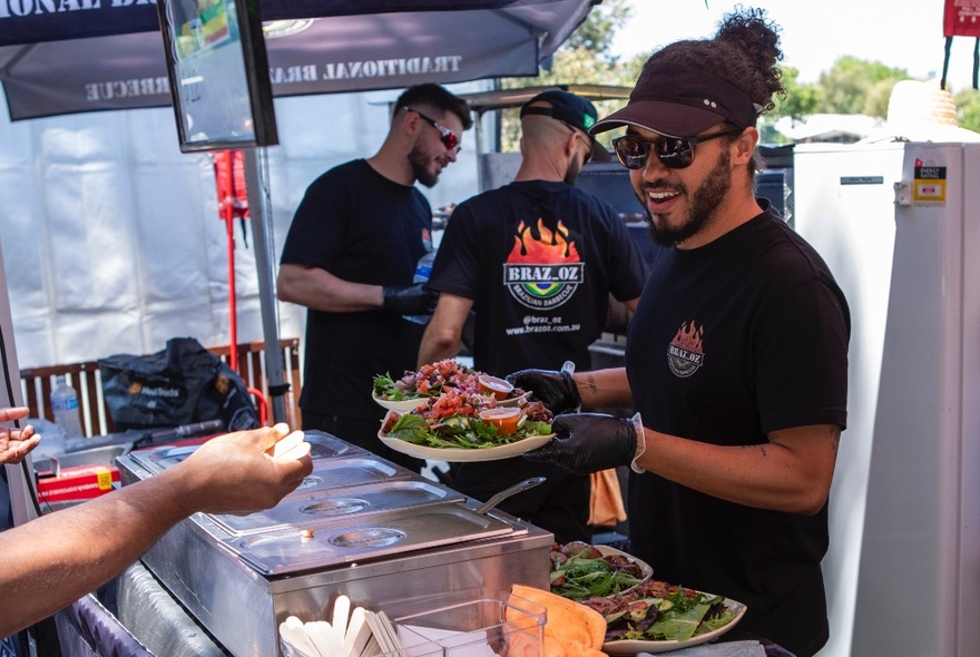 Three men cooking at an outdoor food stall. 