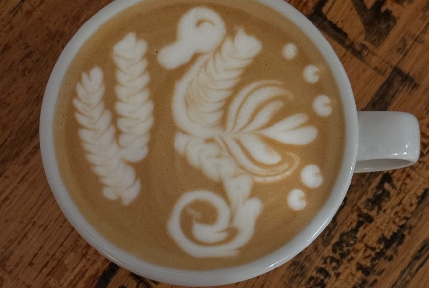 Cup of coffee with latte artwork of a seahorse with seaweed.