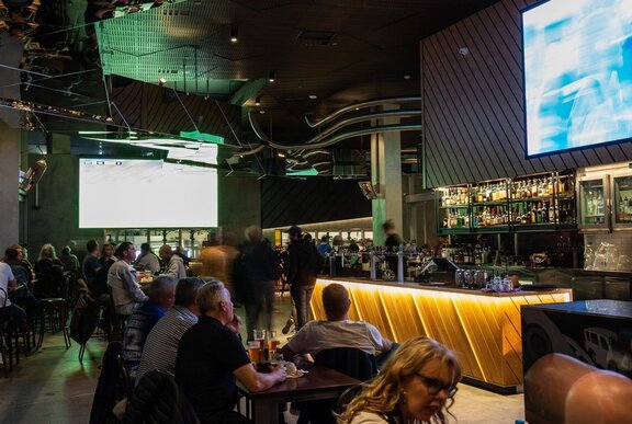 The interior of a modern sports bar with huge viewing screens.