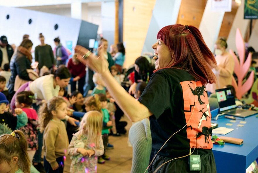 A person performing in front of a crowd of young children and their adult guardians, inside Melbourne Museum.