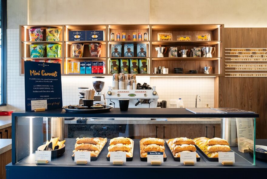 Cafe interior with display shelves and counter filled with cannoli.