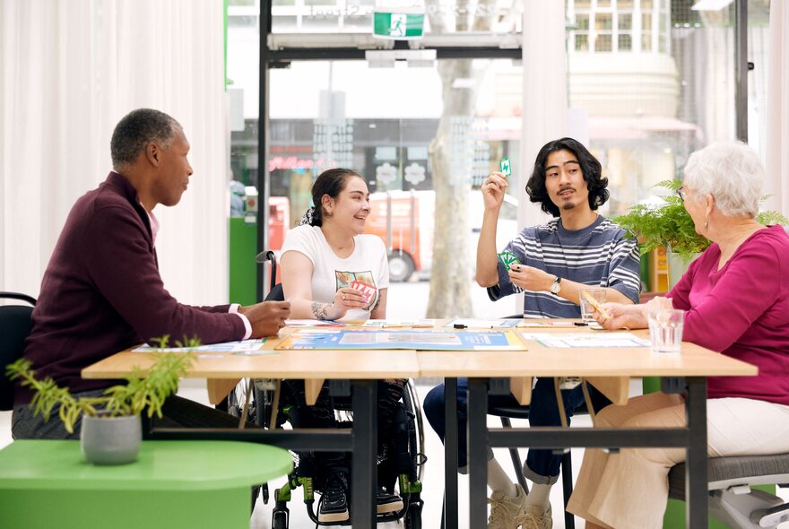 Four demographically different people sitting at a table together having a discussion.