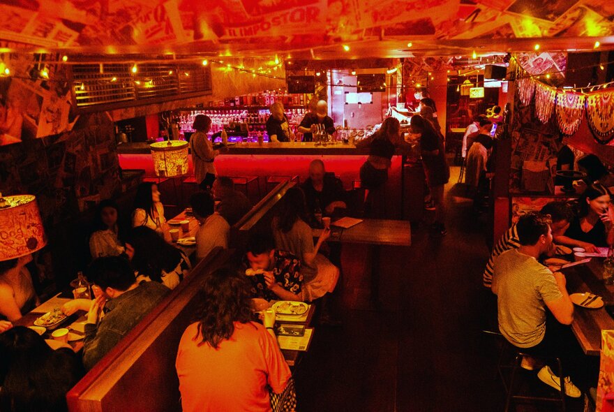 People sitting in a dark bar with neon red lighting.