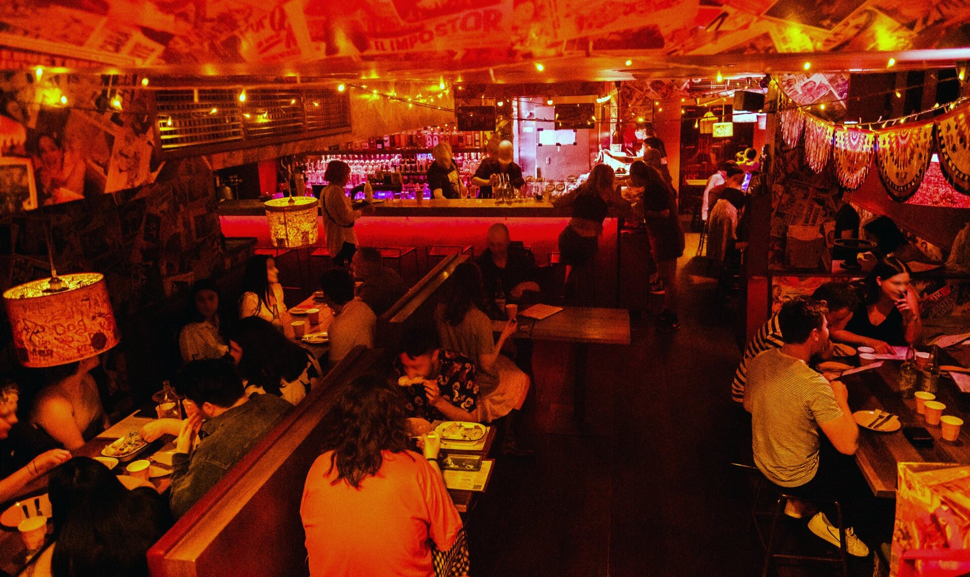 People sitting in a dark bar with neon red lighting.