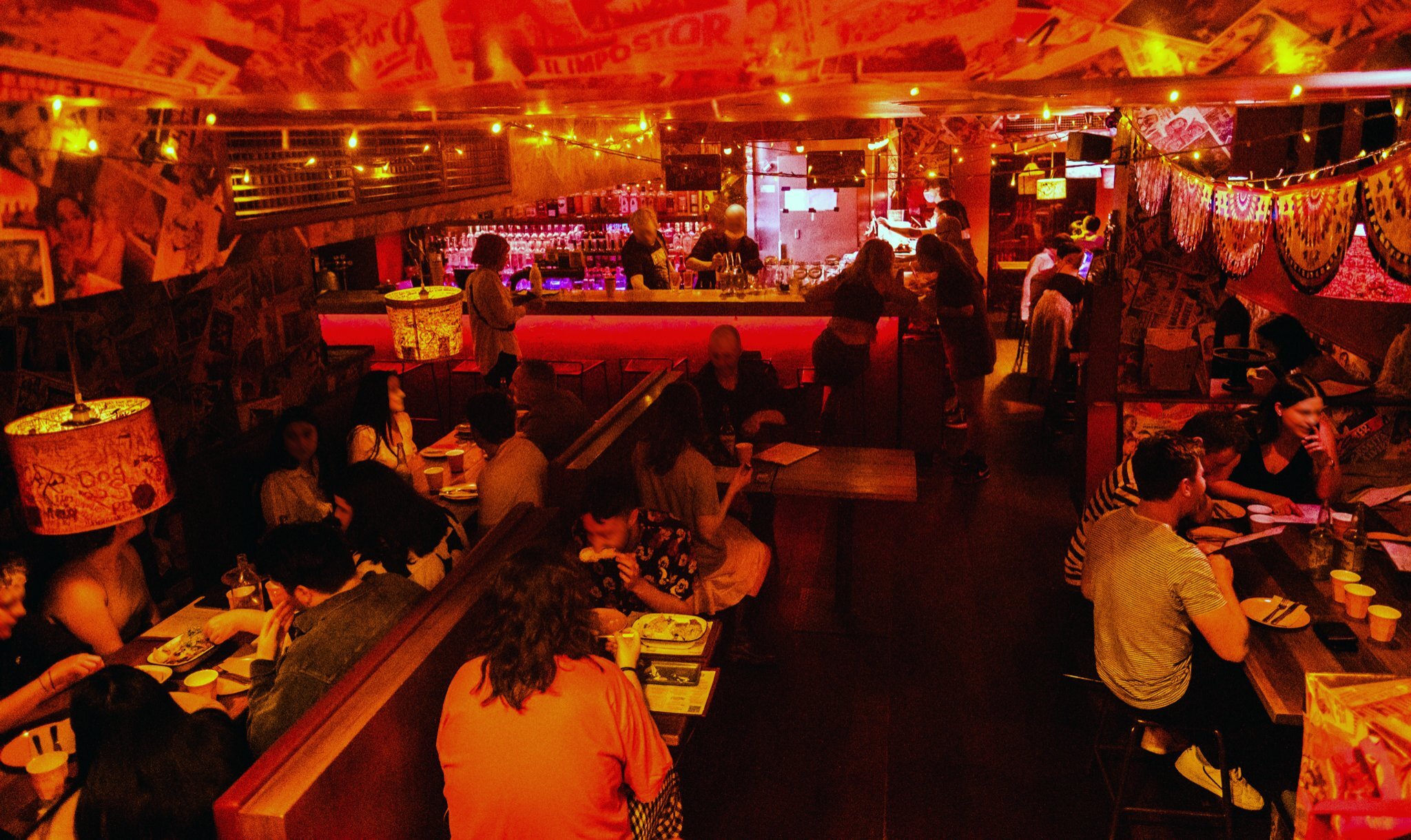 People sitting in a dark bar with neon red lighting.