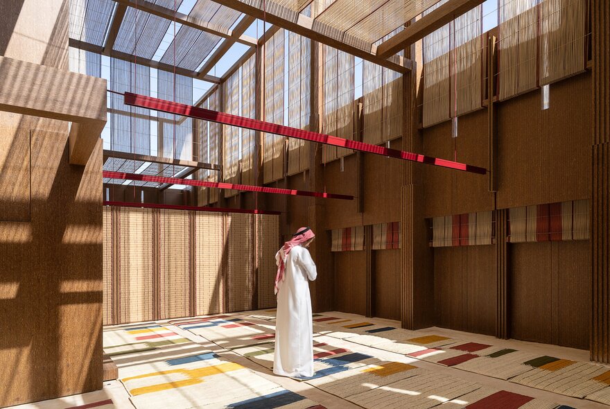 A man in a room with plant fibre wall and floor decorations.