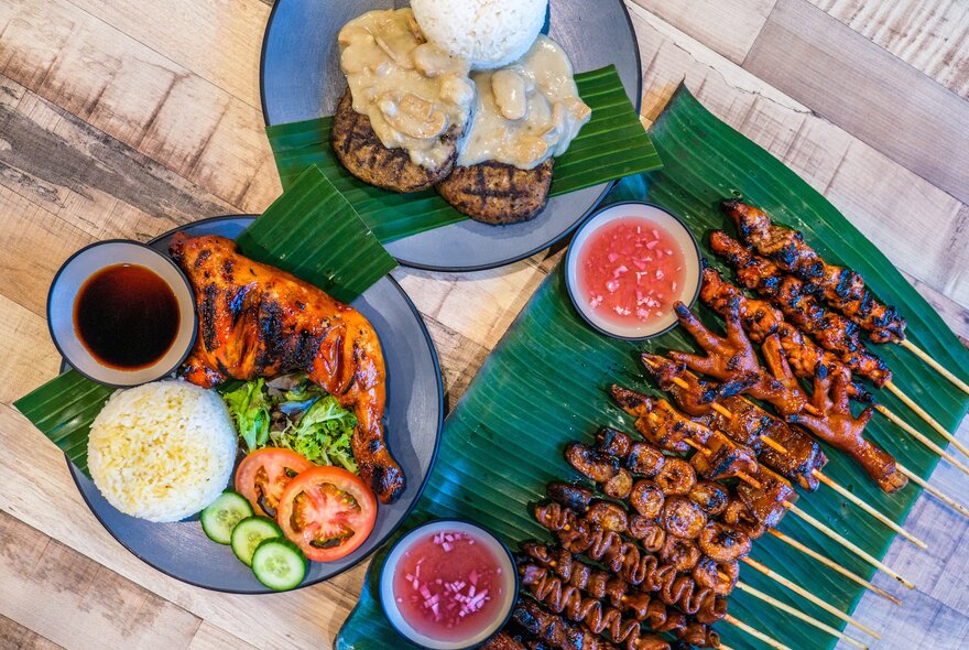 An assortment of Filipino dishes including grilled chicken, burger steaks and skewers.