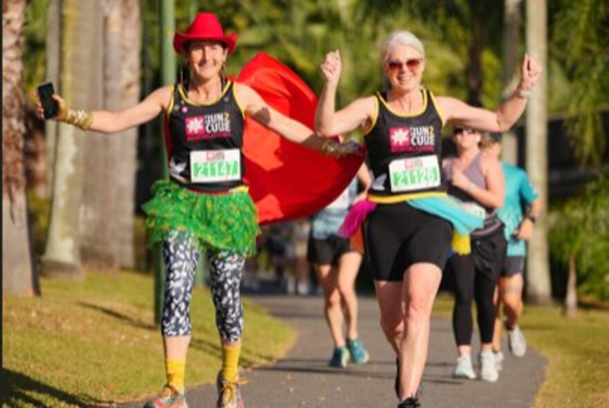 Two women smiling and wearing fun clothes during a charity fun run. 