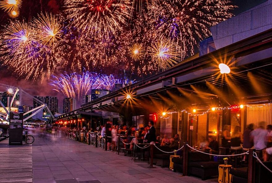 A dining area with fireworks going off overhead.