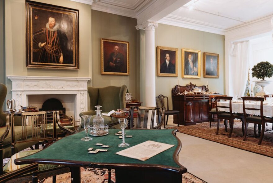 A room at The Johnson Collection Georgian mansion with a fireplace, a leather armchair, a dining table, rugs, objects d'art and paintings on the wall.
