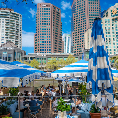 An outdoor restaurant on the river with blue and white umbrellas.