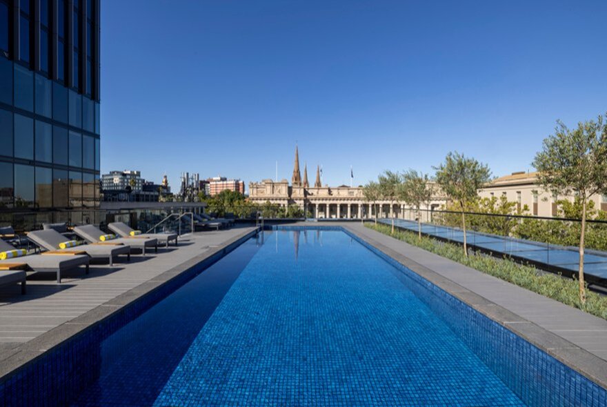 Rooftop pool deck at Le Méridien Melbourne with lounge deck chairs and a large blue pool.