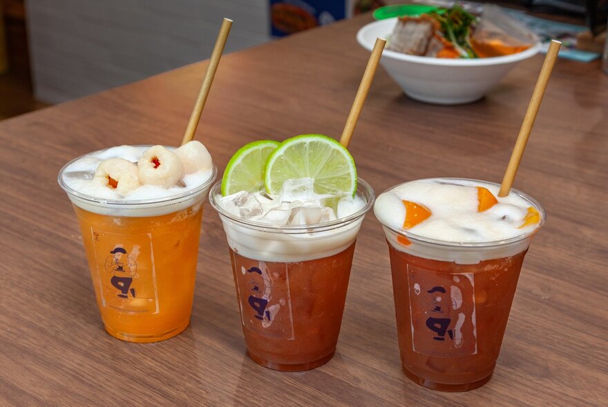 Three takeaway Asian drinks with straws.