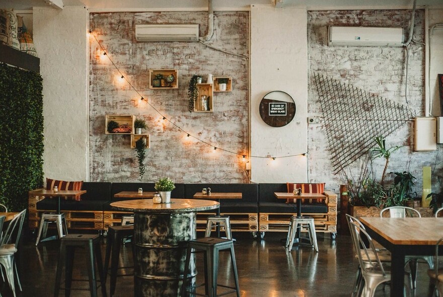 Cafe interior with benches, tables and chairs, distressed brick walls and wall displays.