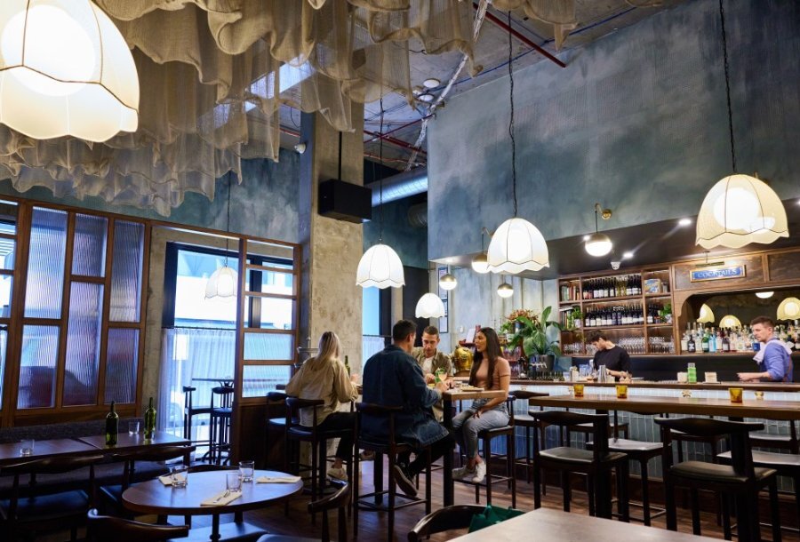 People dining on high tables in a glamourous restaurant with pendant lights.